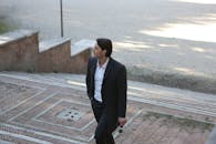 一位身穿黑色西装的商人自信地走上户外的砖砌楼梯