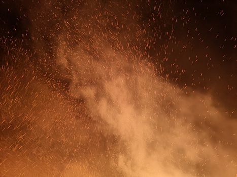 A captivating image of fire sparks and smoke filling the night sky, creating a dynamic and dramatic scene.