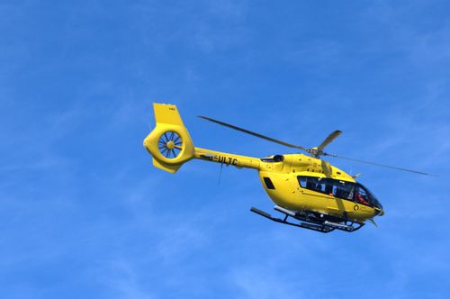 Free Bright yellow helicopter in flight against a clear blue sky. Stock Photo