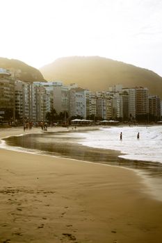 Sunset view of Copacabana Beach with city skyline and distant mountains.