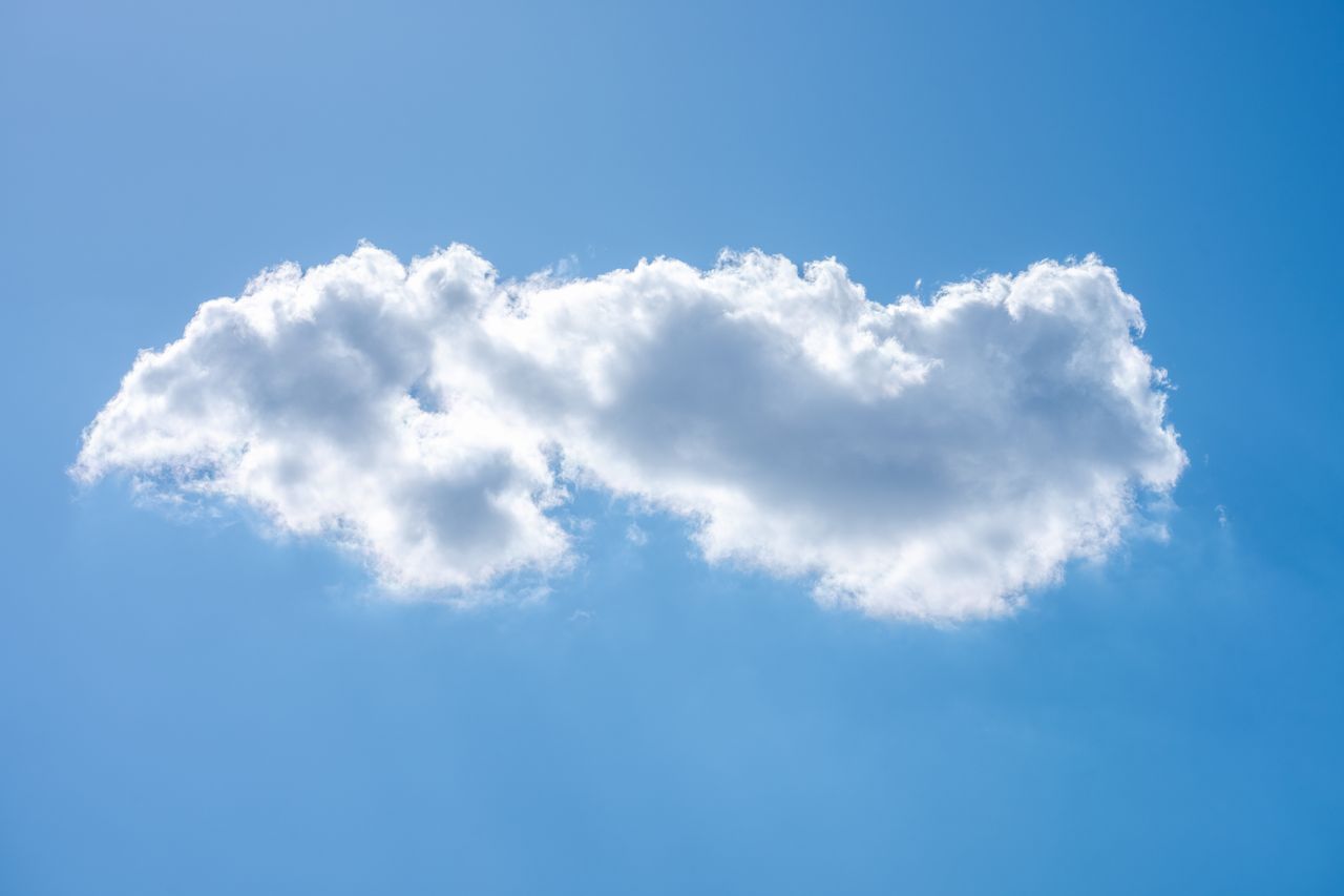 a crisp clear blue sky with a single fluffy white cloud floating peace