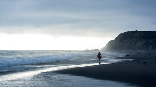 一個女人在海邊散步的剪影照片