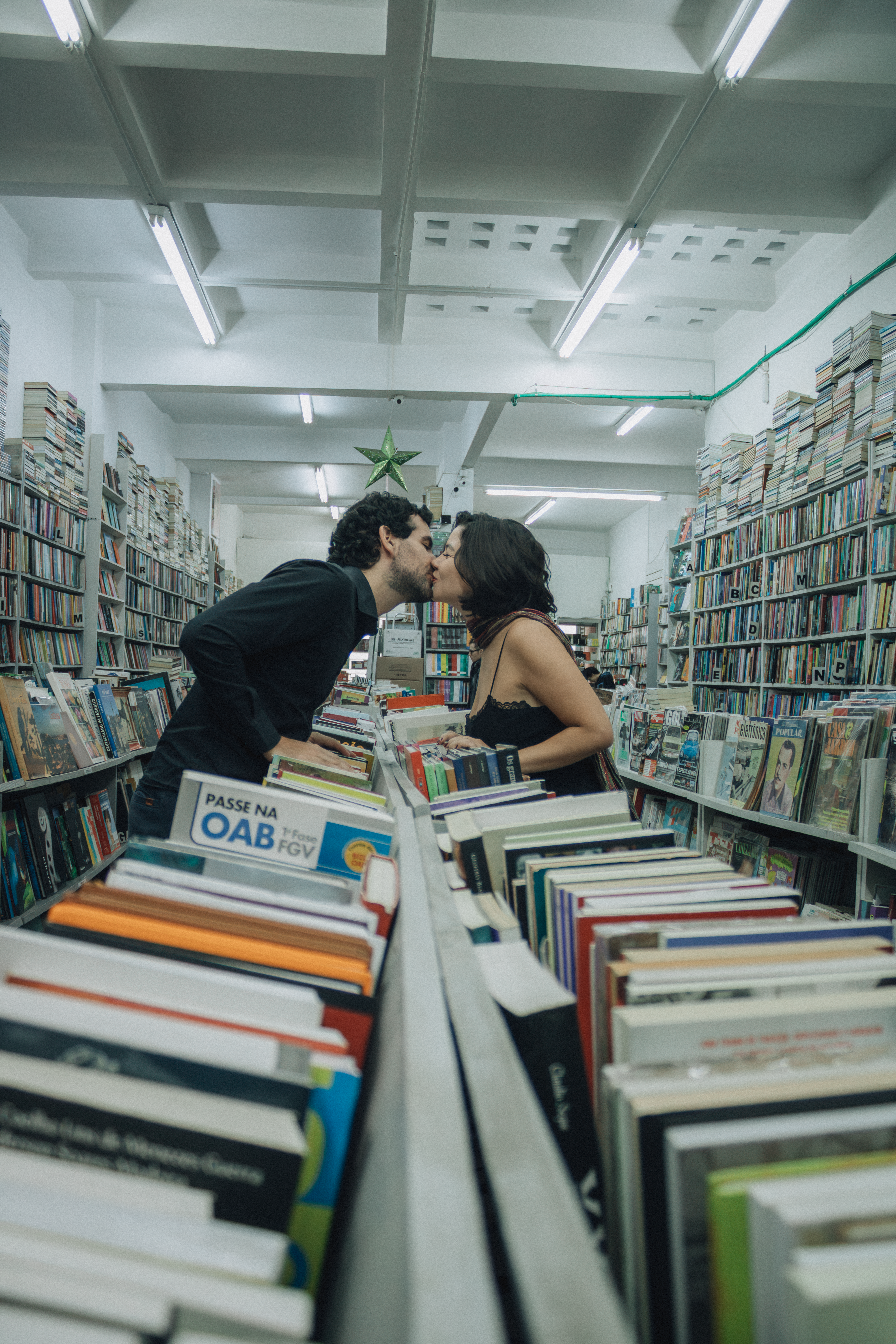 A romantic kiss between a couple in a library surrounded by books.