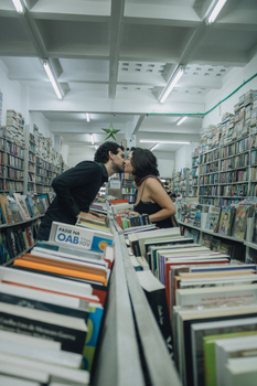 A romantic kiss between a couple in a library surrounded by books.