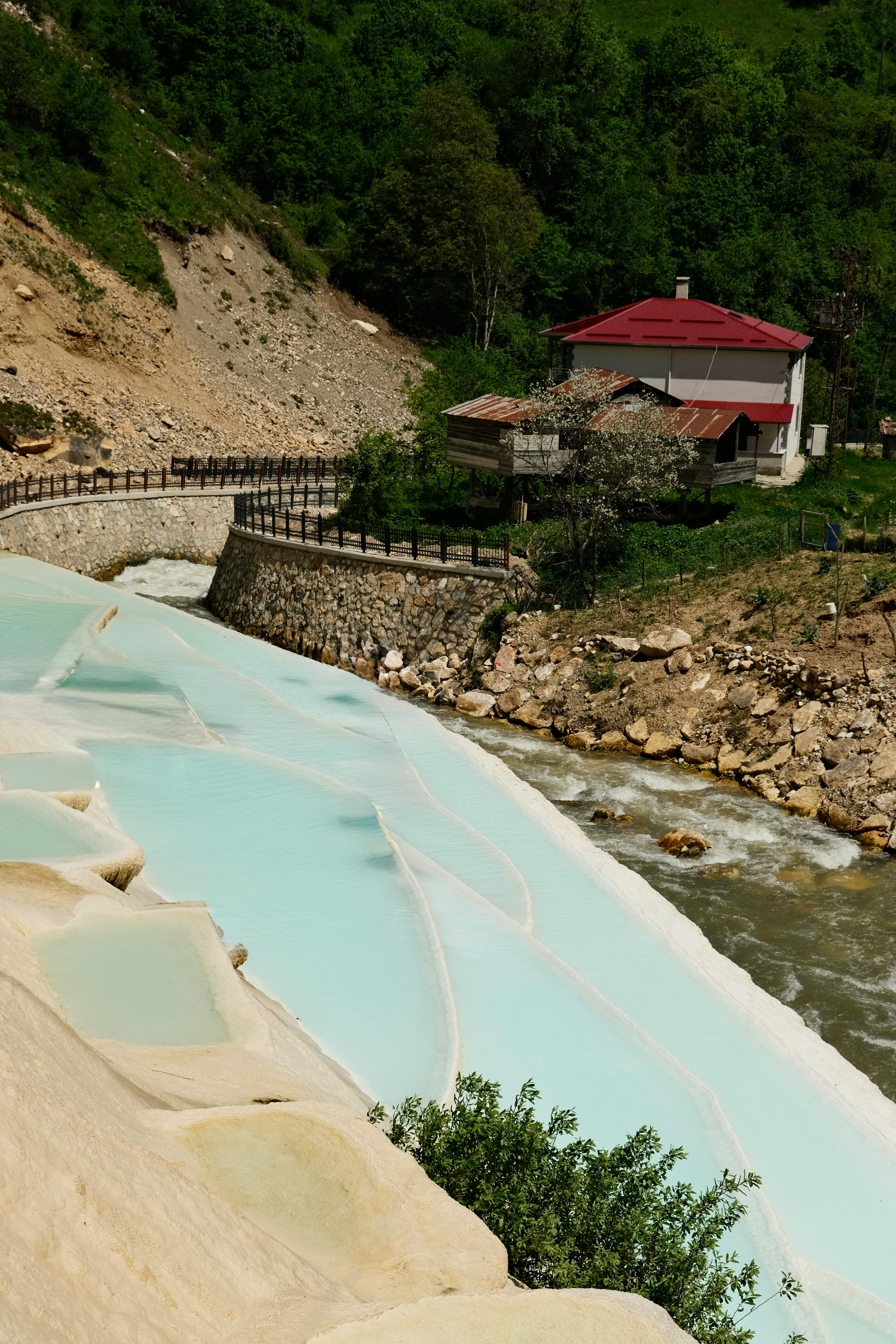Beautiful travertine terraces by Mavi Göl in Giresun, Türkiye with lush greenery and a charming house.