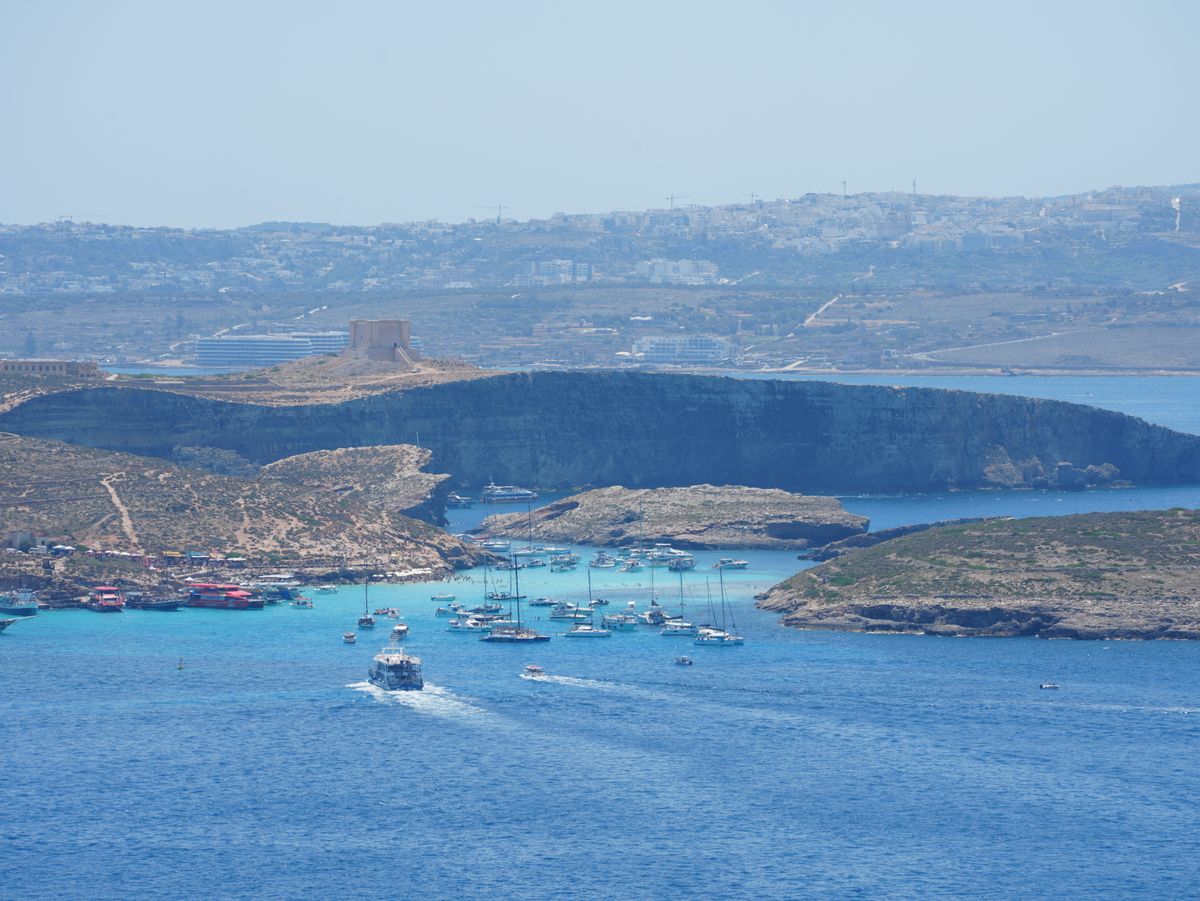 Blue Lagoon de pe insula Comino, cu apă turcoaz foarte deschisă între maluri stâncoase
