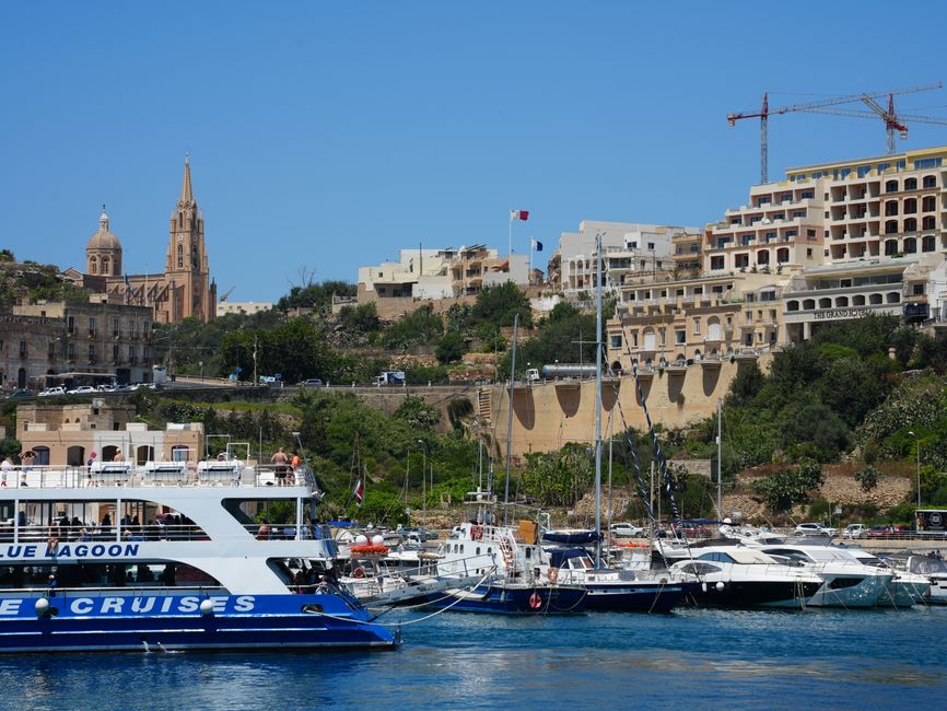 Incredible Private Boat Charter to Comino Blue Lagoon Review: An Unforgettable Malta Sailing Experience Review 2026 - Boats docked at Mgarr Harbour in Gozo, Malta with church and buildings in the background.