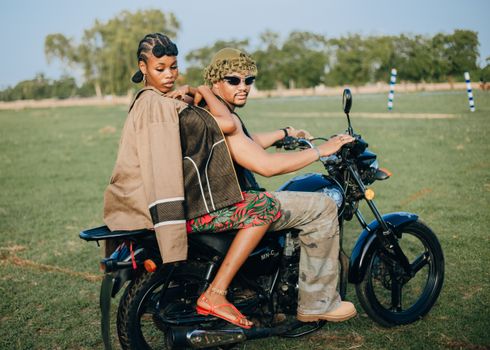 Fashionable couple on a motorcycle enjoys a sunny day in Zaria, Nigeria.