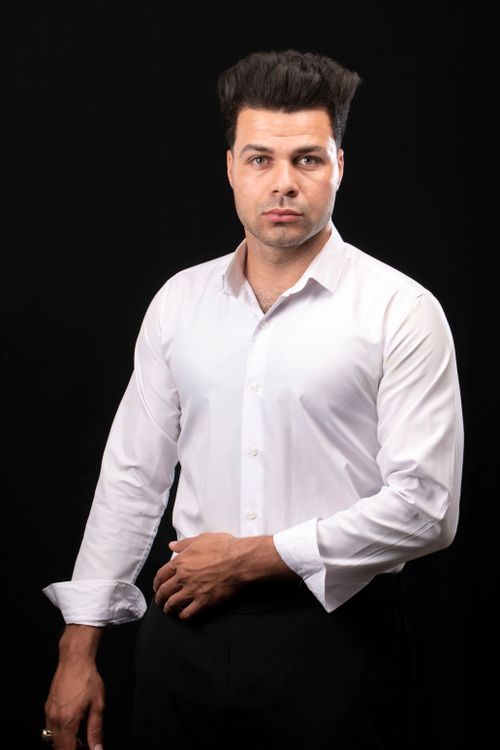 Free Portrait of a confident man in a white shirt with a black backdrop, conveying professionalism. Stock Photo