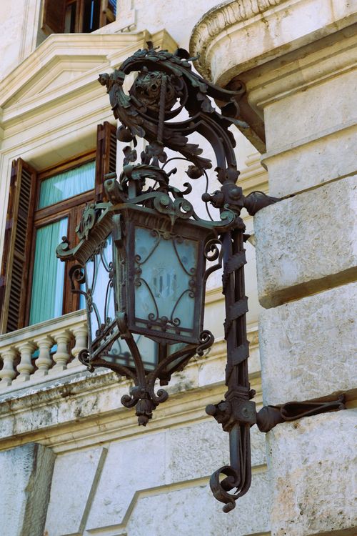 Free Vintage wrought iron lantern mounted on a historic stone building facade. Stock Photo