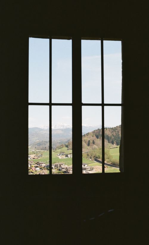 Free Captivating view of a mountain landscape through a window, featuring clear skies and lush greenery. Stock Photo
