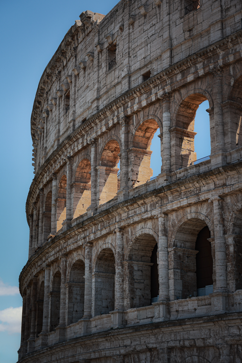 Free A close-up view of the historic Colosseum in Rome, showcasing its ancient architecture under a clear blue sky. Stock Photo