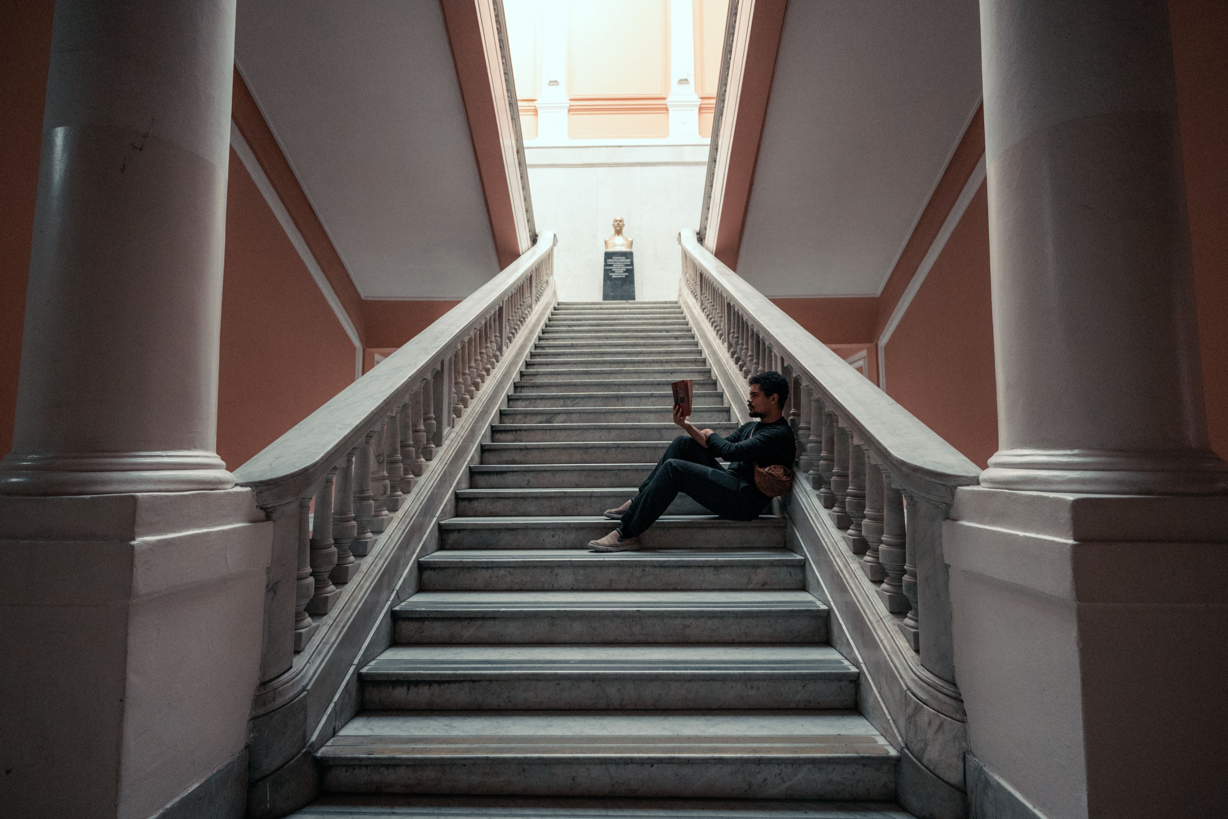 A student sits reading on a grand staircase in a Buenos Aires university.