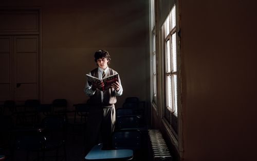 Free A student stands by a window reading in a dimly lit Buenos Aires classroom. Stock Photo