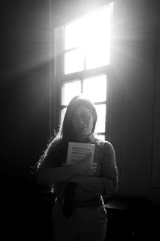 A student stands in a sunlit room holding a book on Argentine history.