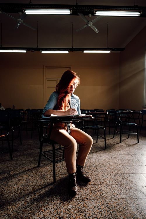 Free A student writes in a dimly lit Buenos Aires classroom, capturing a focused moment. Stock Photo