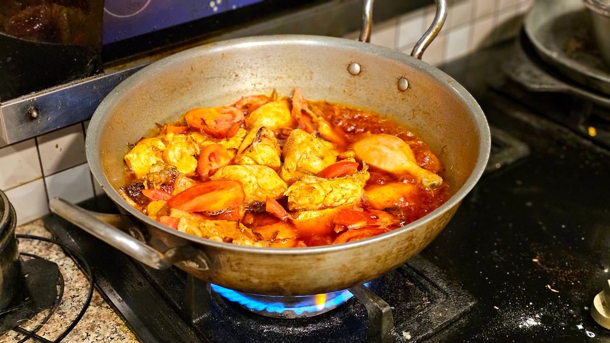 Chicken stew with tomatoes sizzling in a skillet on the stovetop