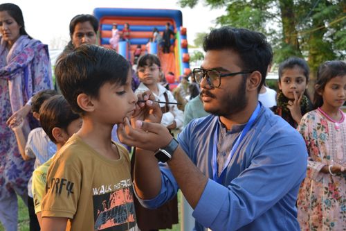 Free A group of children participating in a face painting activity at an outdoor gathering in Taxila, Pakistan. Stock Photo