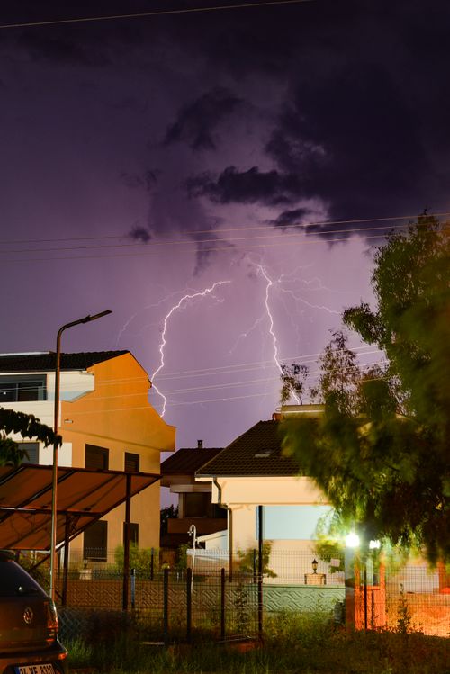 Free Striking lightning illuminates the night sky over residential homes in Ayvalık, Turkey, creating a dramatic scene. Stock Photo