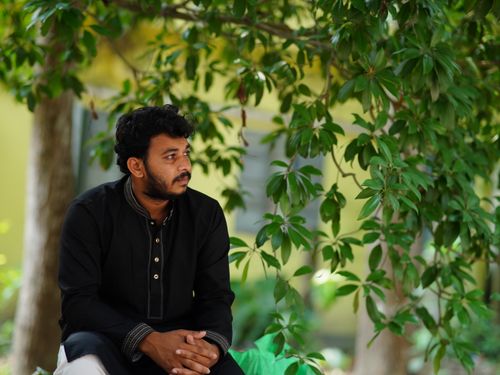 Free A man in traditional attire sits thoughtfully under a tree outdoors in Dhaka, Bangladesh. Stock Photo