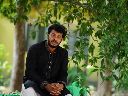 Free A man sits under a tree in traditional attire, showcasing a serene outdoor setting. Stock Photo