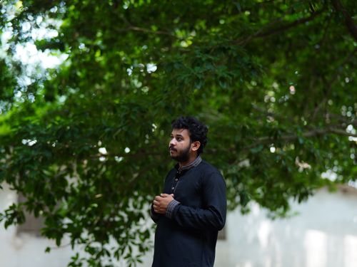 Free A thoughtful man stands under lush green trees in Dhaka, Bangladesh, wearing traditional clothing. Stock Photo