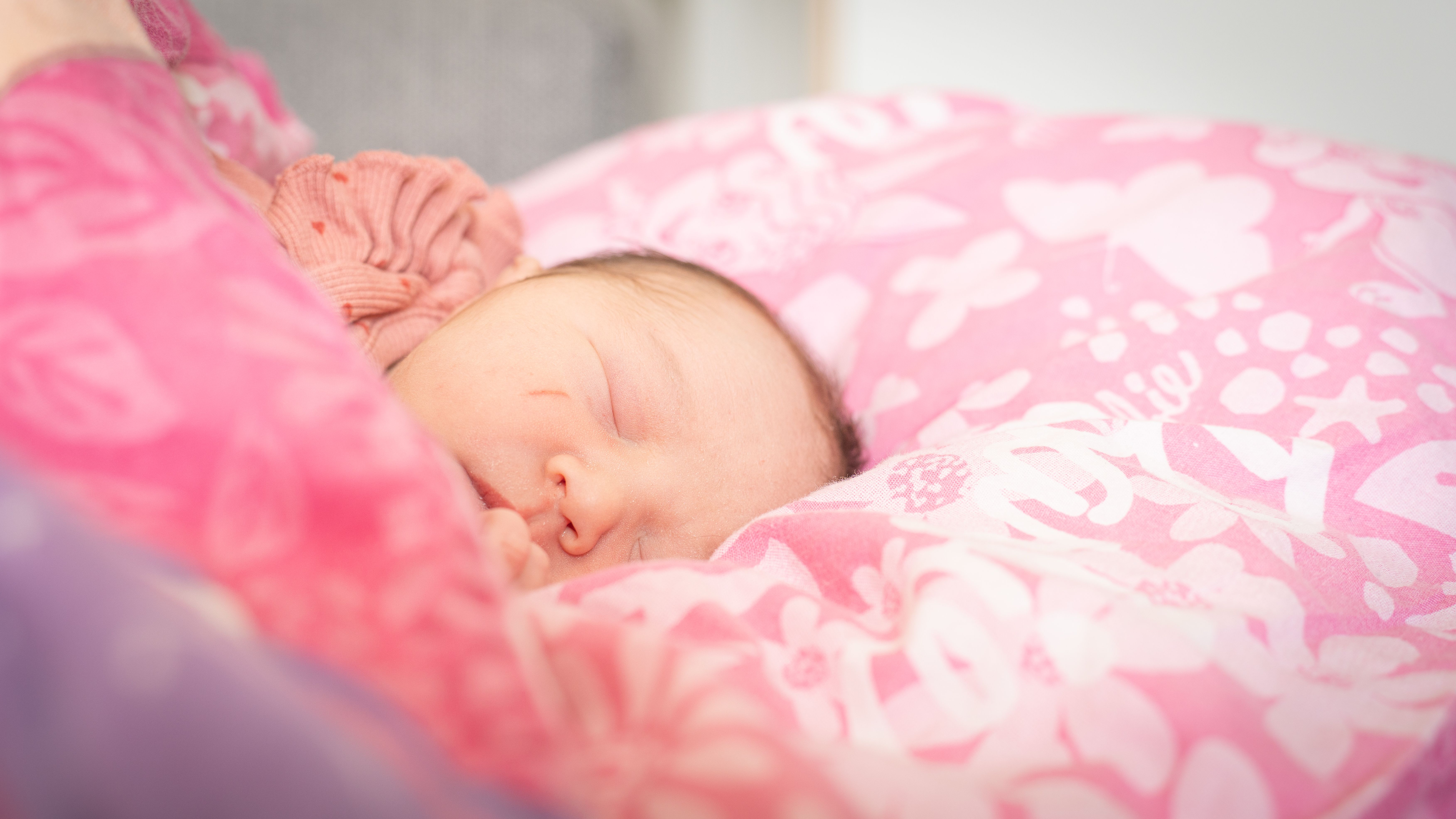 Mother gently holding newborn baby in hospital setting, showcasing warmth and love.