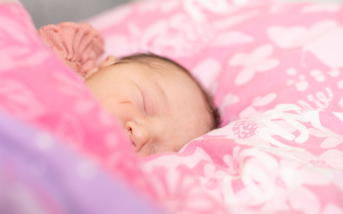 A serene portrait of a sleeping baby nestled on a pink-patterned pillow, capturing tranquility.