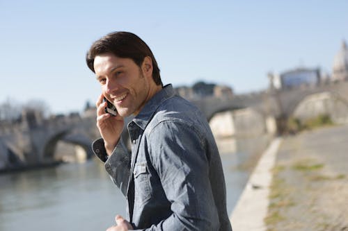 Uomo In Camicia Grigia Usando Il Suo Cellulare