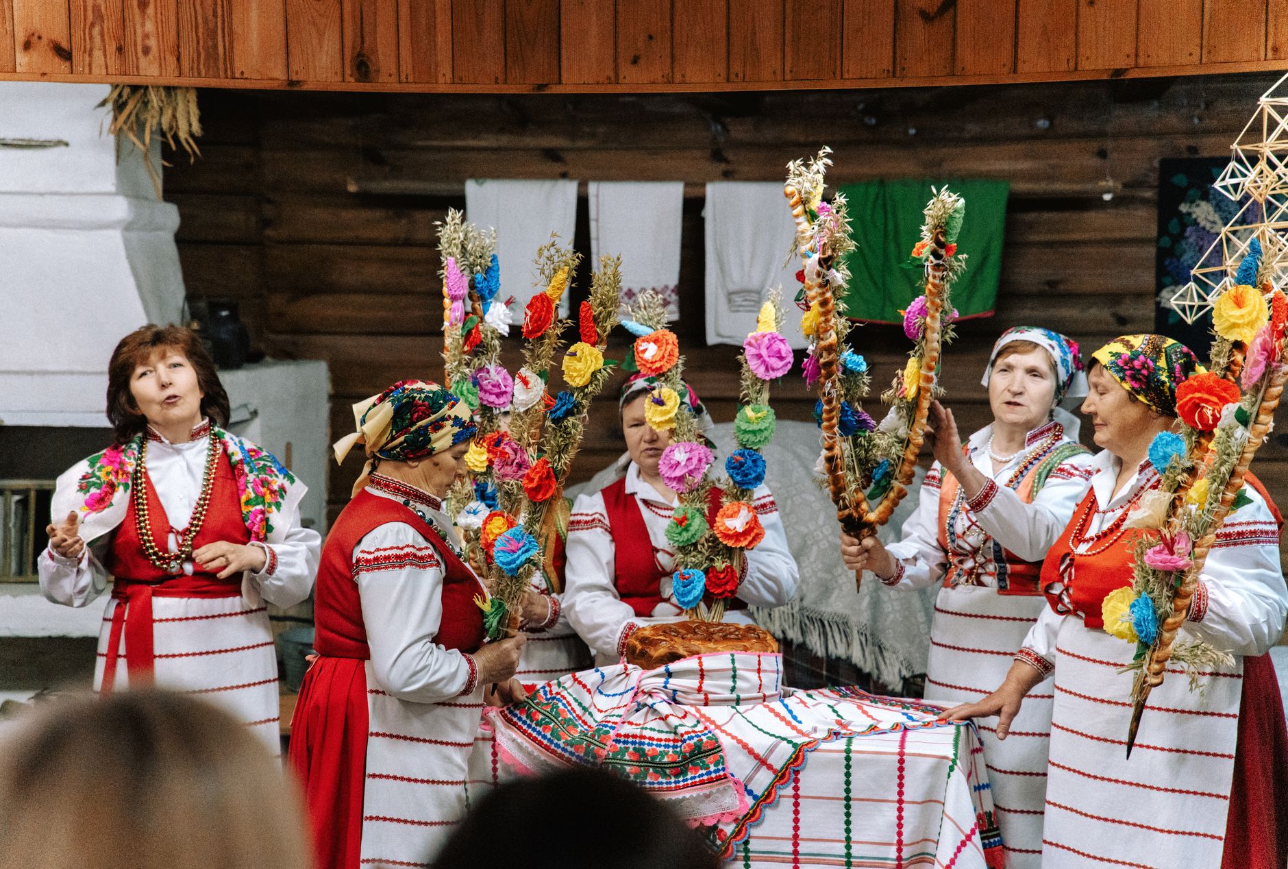 Five women in traditional attire holding vibrant decorations in a cultural celebration.