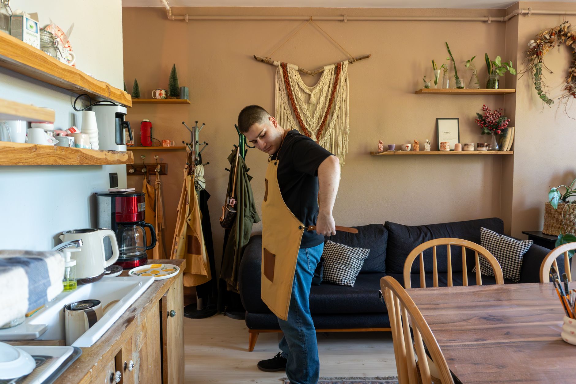warm apartment decor with DIY hacks A man adjusts his apron in a warm, inviting kitchen setting. Home cooking preparation.