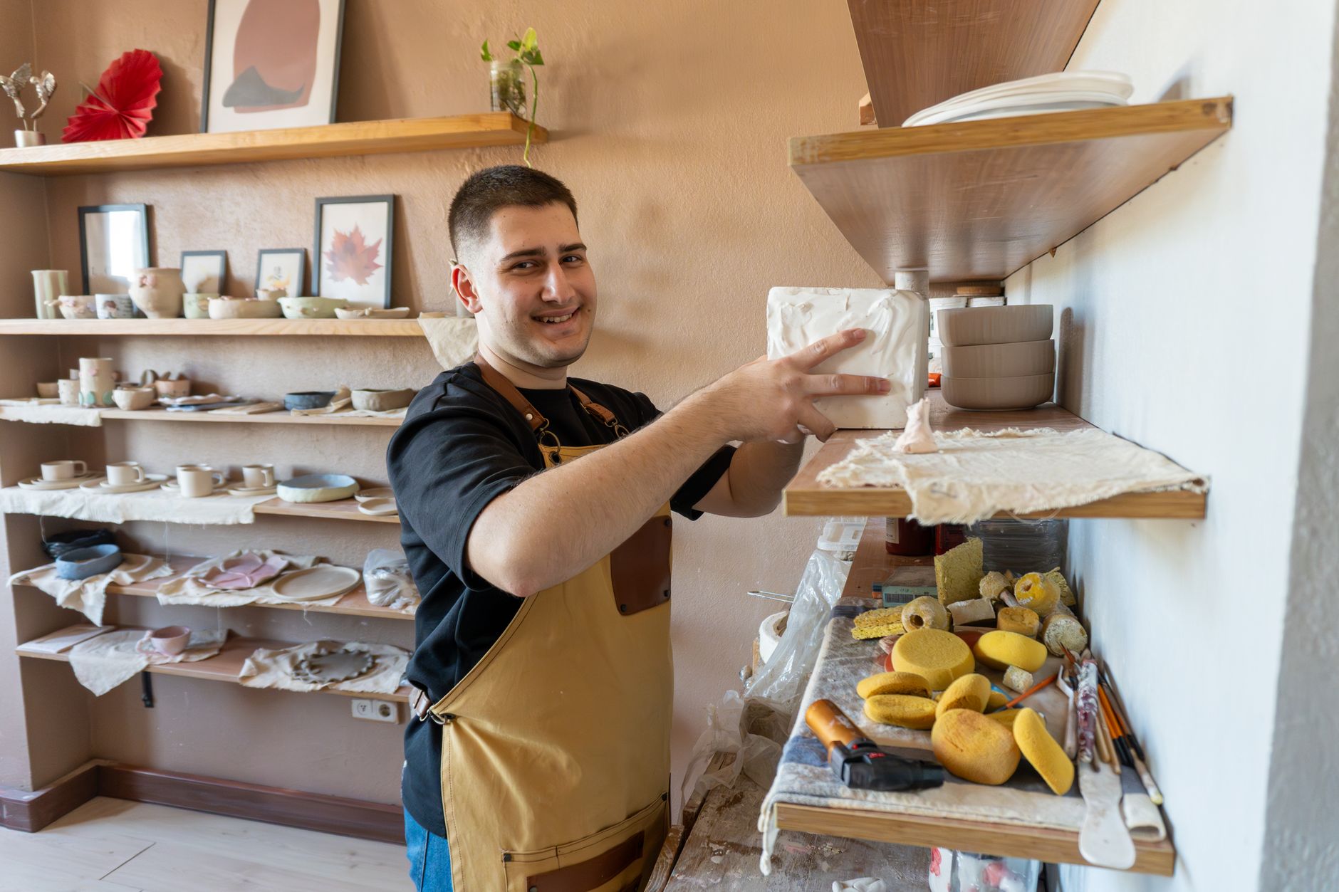 Young potter arranging ceramics on studio shelves
