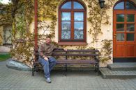 A man sitting on a bench beside an ivy-covered building in Pinsk, Belarus. Captured in an urban outdoor setting.