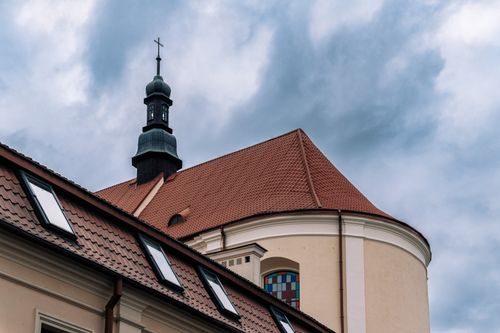 Free A historic church steeple with a red tile roof in Pinsk, Belarus, under a dramatic cloudy sky. Stock Photo