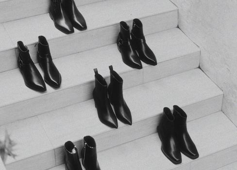 A stylish arrangement of black leather boots on a white staircase, emphasizing fashion and minimalism.