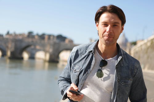 Man in Grey Denim Jacket Holding Smartphone