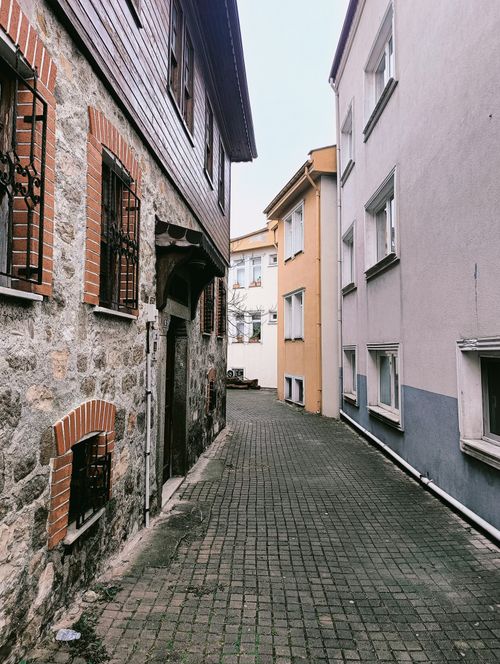 Free A narrow cobblestone alleyway lined with historic stone and brick buildings in a quaint European town. Stock Photo