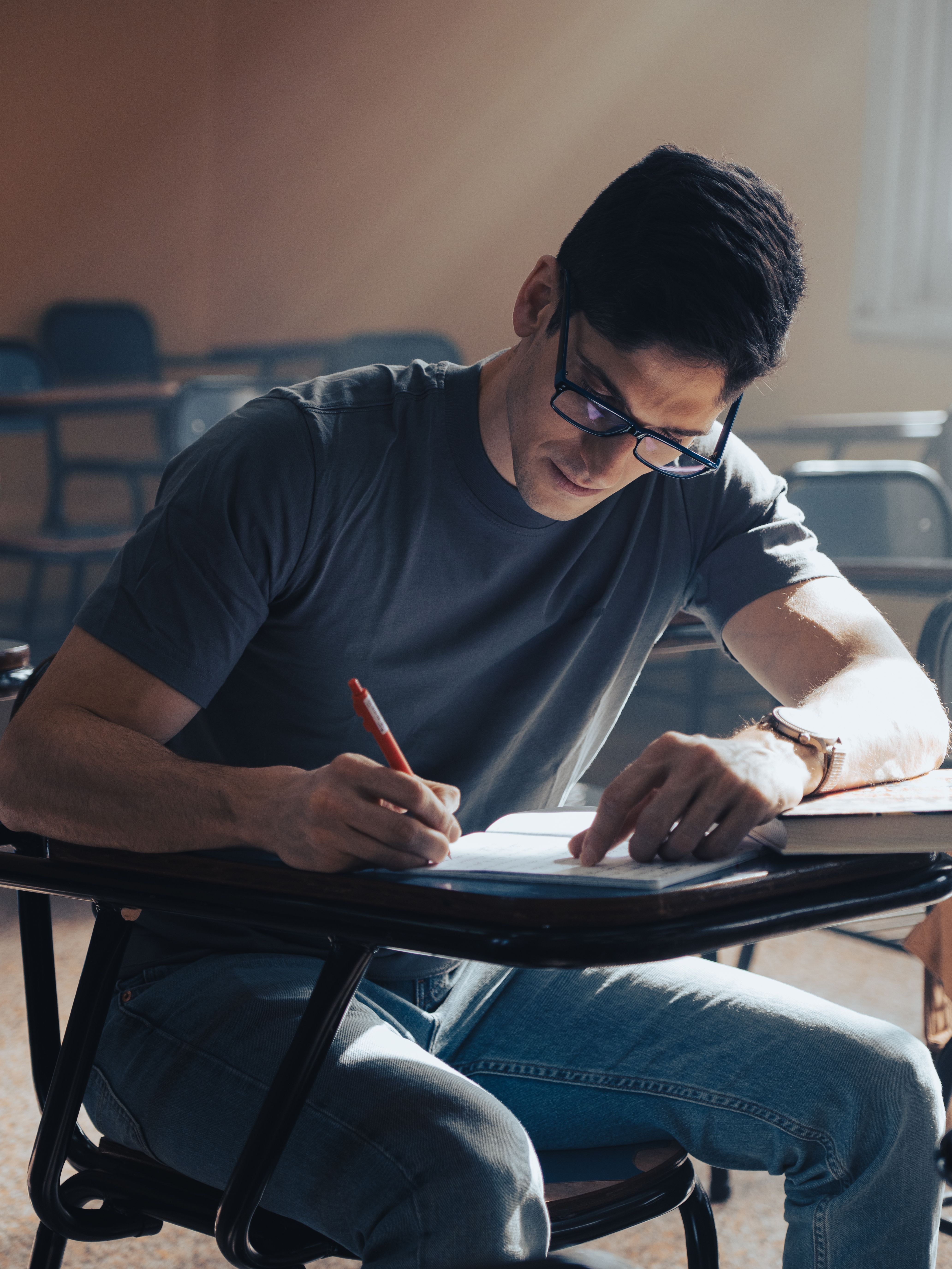 Young adult student concentrating on notes in a classroom at daytime.