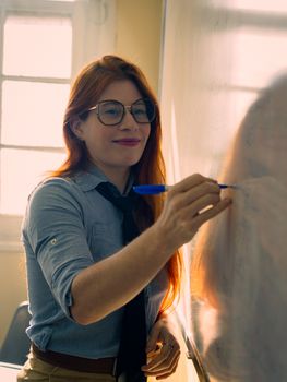 Confident teacher writing on a blackboard in a sunny classroom in Buenos Aires.