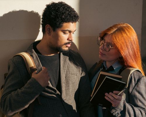 Free Two students discuss notes, sunlight illuminating their faces in Buenos Aires. Stock Photo