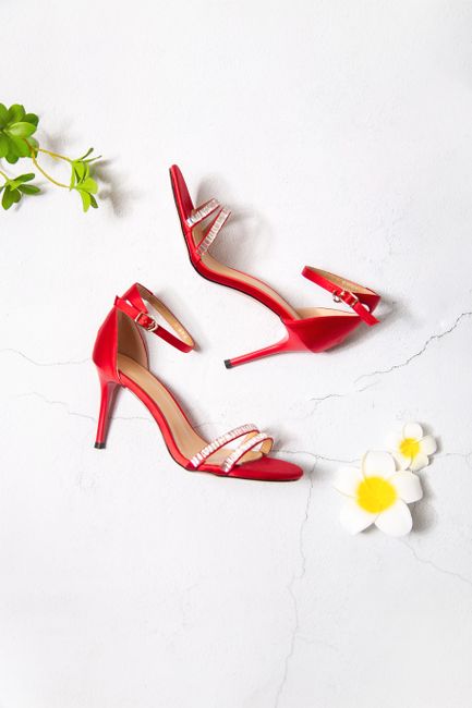 A pair of stylish red high heels paired with flowers on a light background.