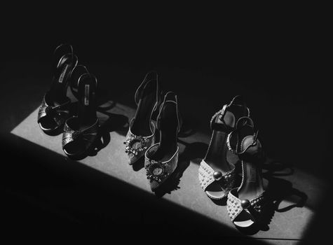 Dramatic black and white photo showcasing elegant bridal shoes in moody lighting.