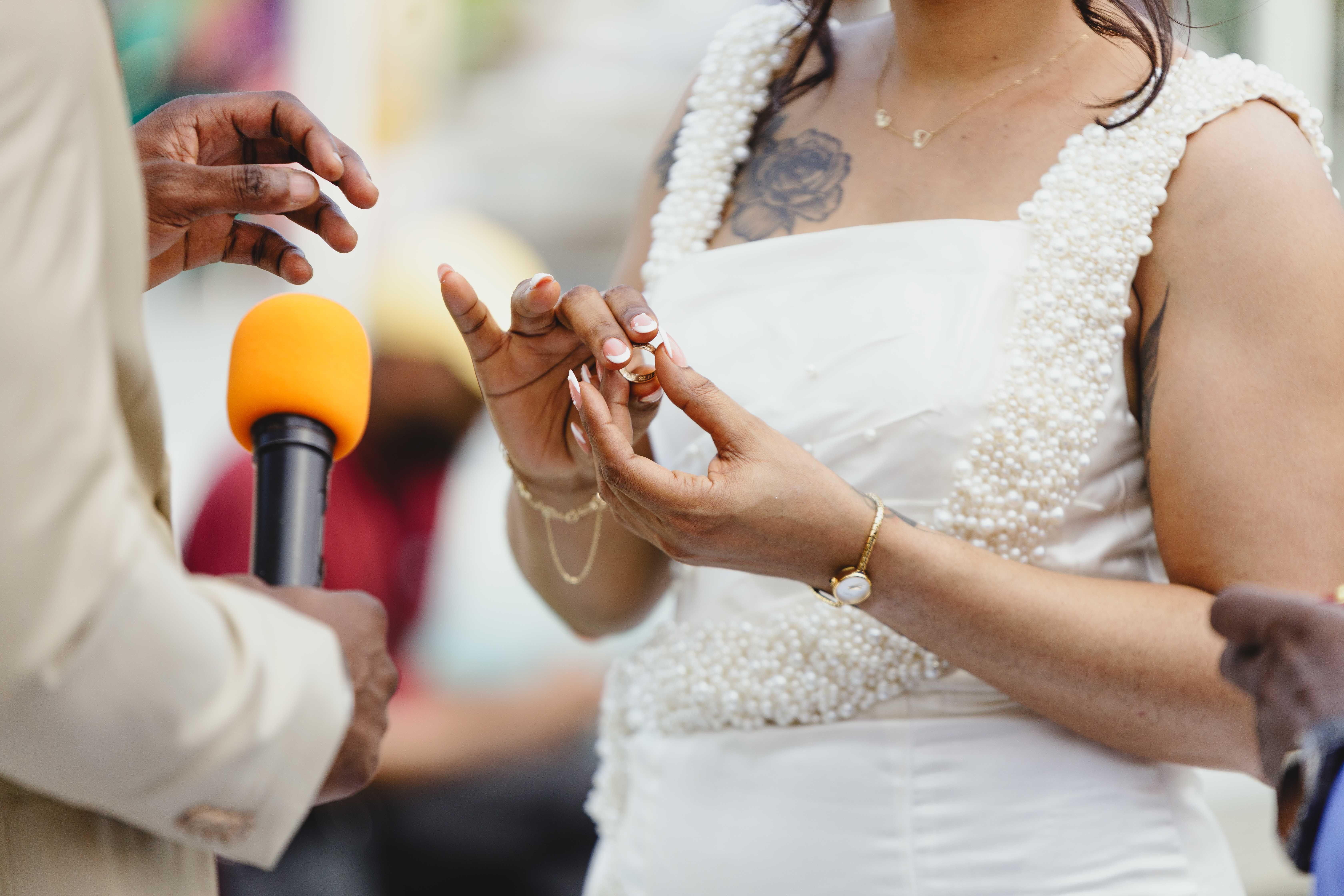 Gouna luxury wedding entertainment — Close-up of ring exchange at an outdoor wedding ceremony focusing on hands and microphon