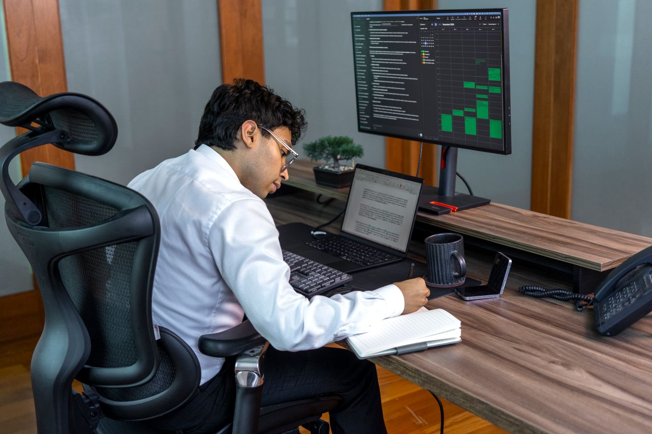 Professional analysing data on computer screens in a real office environment
