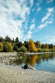 People relaxing by a serene lake in San Carlos de Bariloche during autumn.
