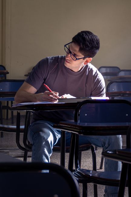 A student concentrating while writing in a quiet classroom setting. A student concentrating while writing in a quiet classroom setting.