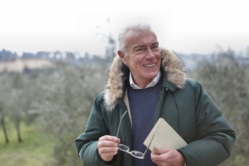 Man in Green and Eyeglasses Jacket Holding Book