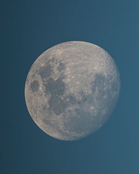 A detailed view of the moon during daytime with a clear sky.