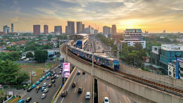 Aerial view of Jakarta's elevated train system during sunset with city skyline in the background.