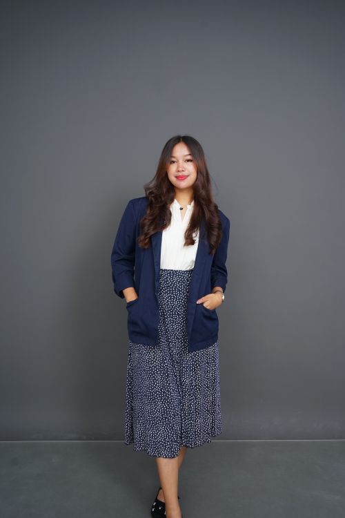 Free Elegant young woman in professional attire standing confidently against a gray background. Stock Photo